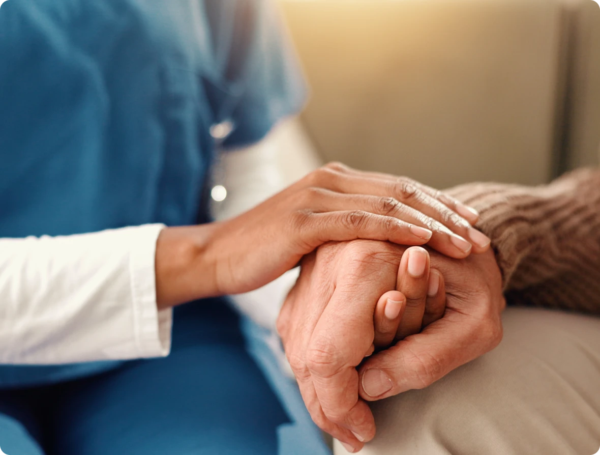 Caregiver holding an elderly person's hand.