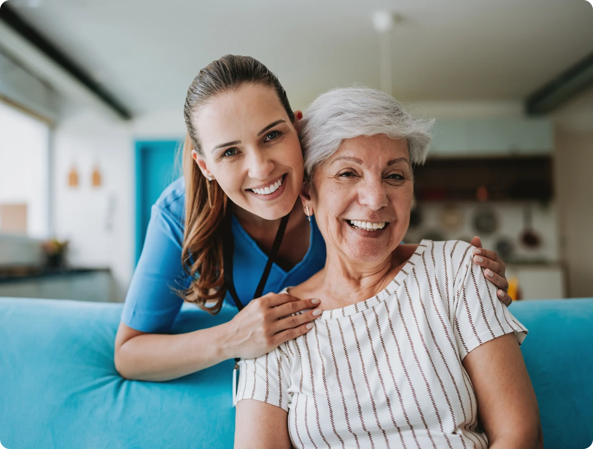 Caregiver and elderly woman smiling together.