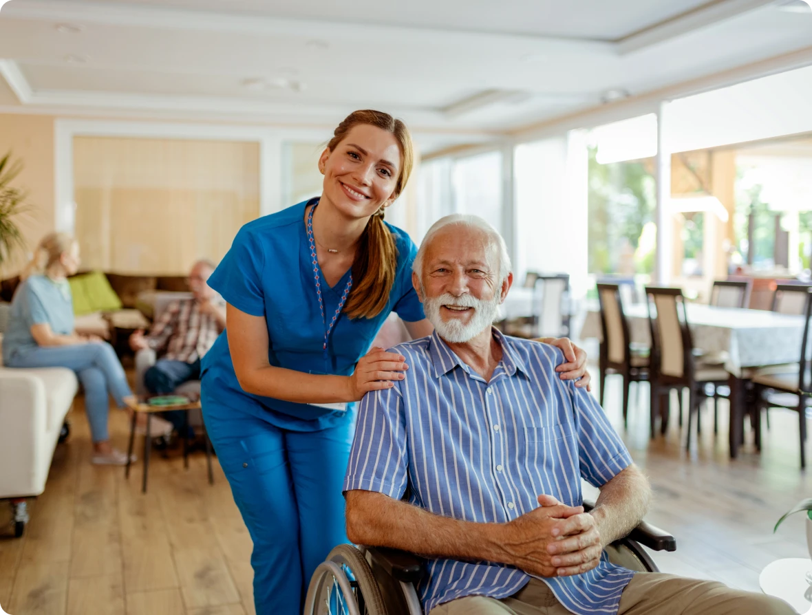 Nurse smiling with elderly man in wheelchair.