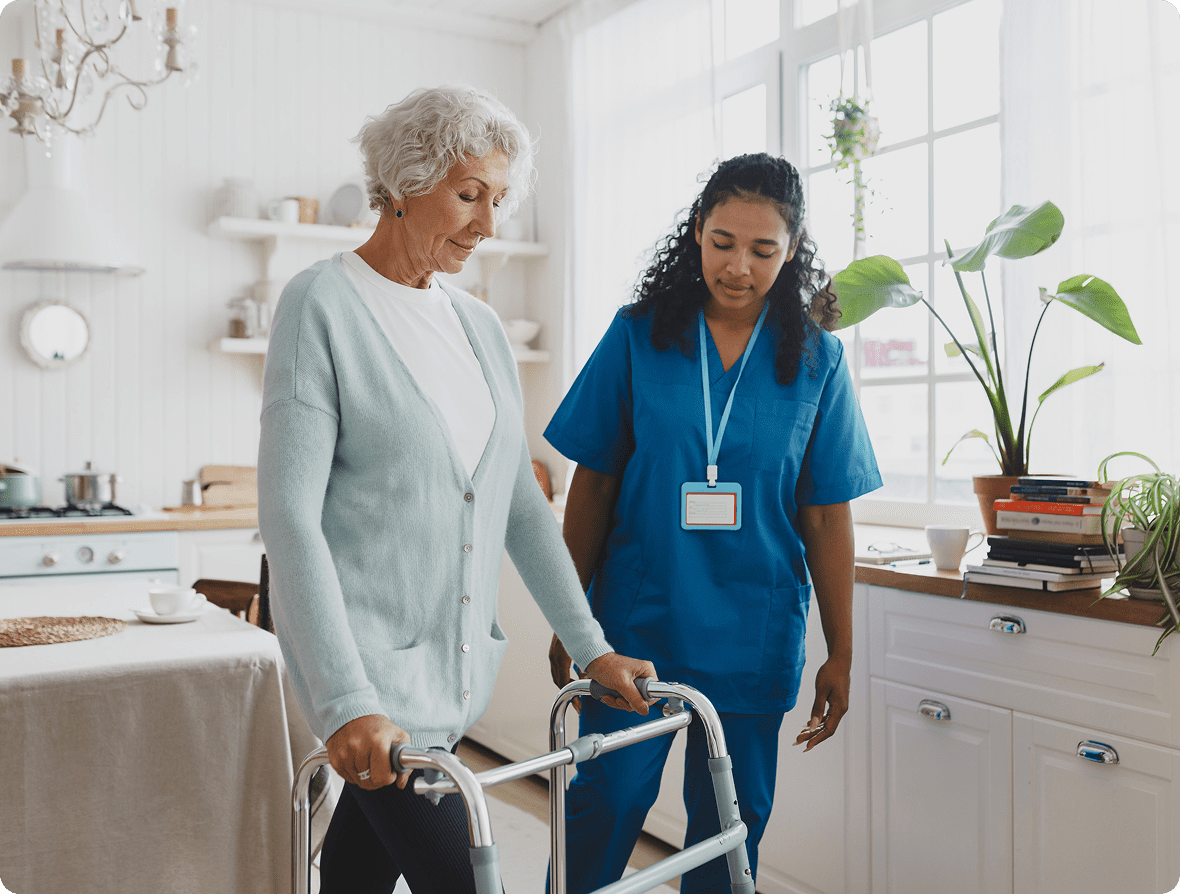 Elderly woman using walker with caregiver assistance.