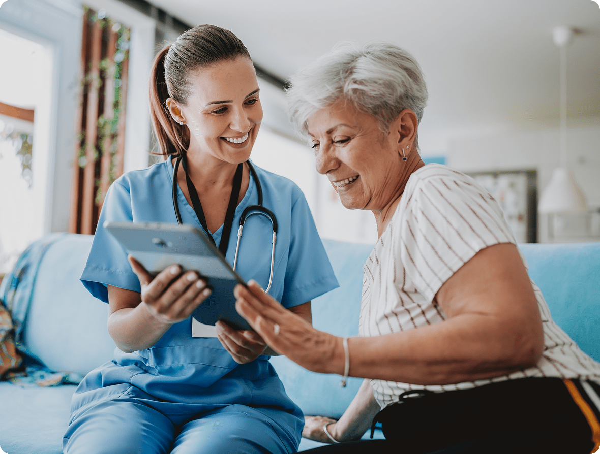 Nurse showing tablet to smiling elderly woman.